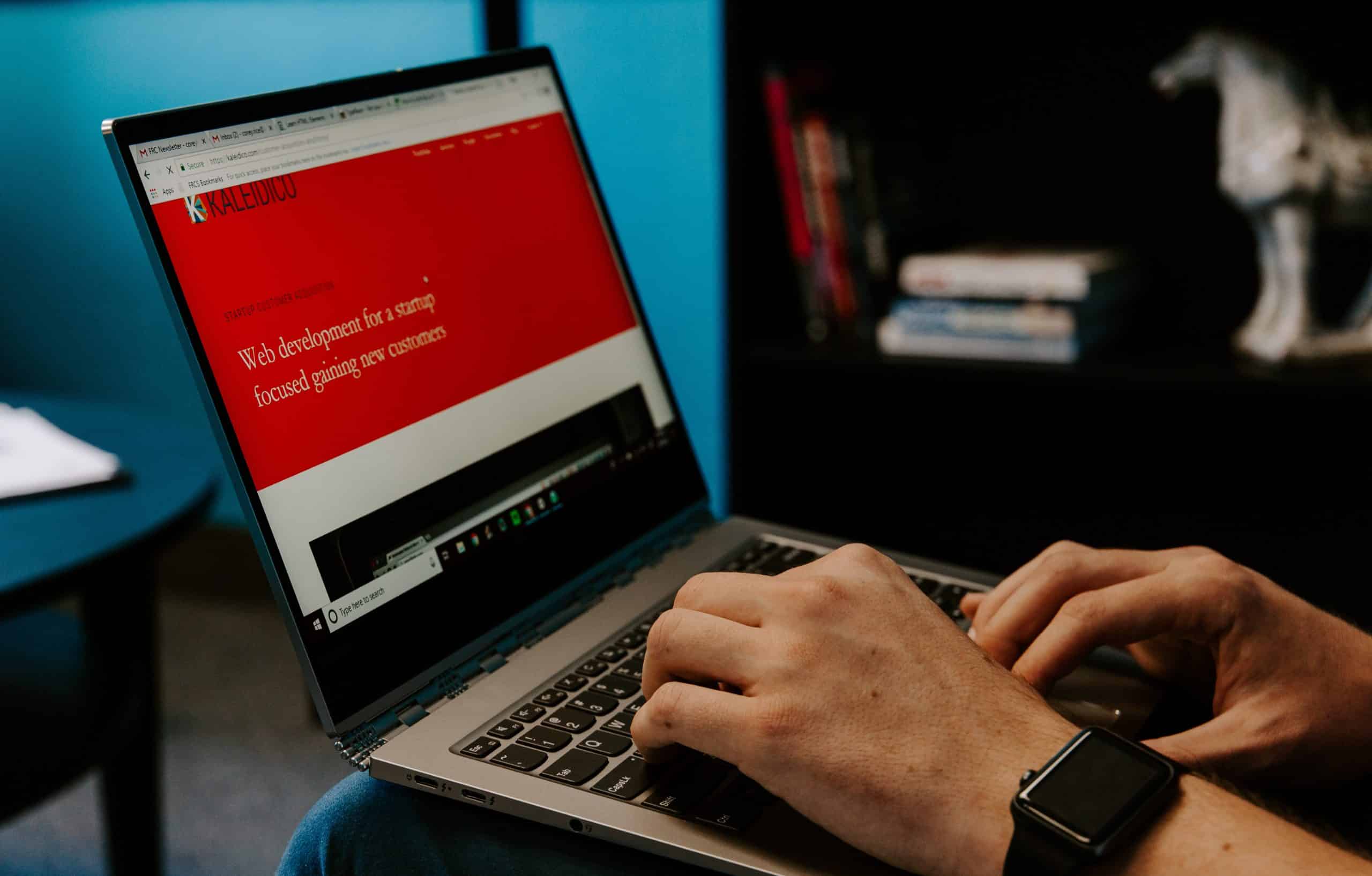 Consultant SEO Montpellier 1 ordinateur qui écrit avec un fond rouge